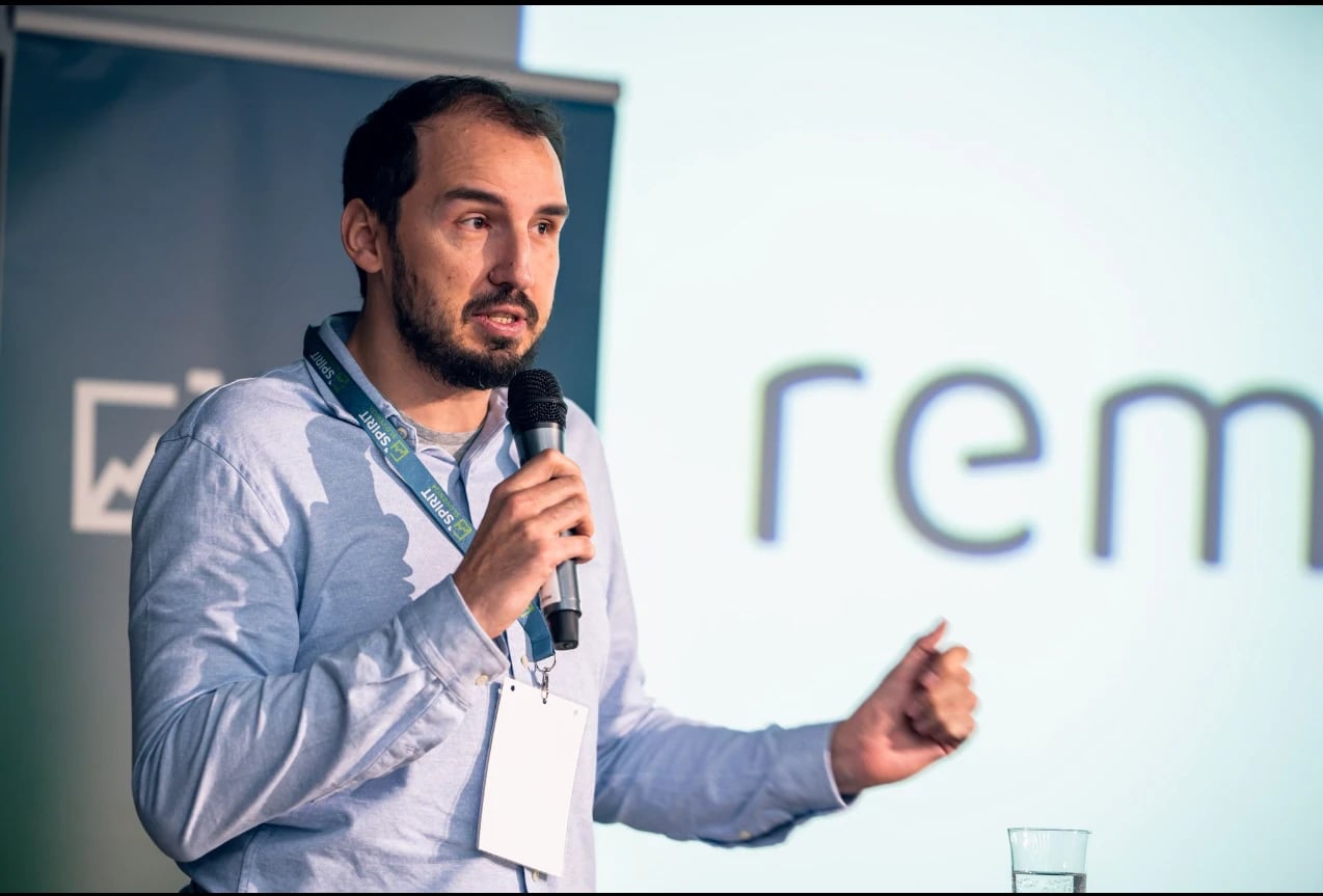 Peter Merc speaking on stage, microphone in hand