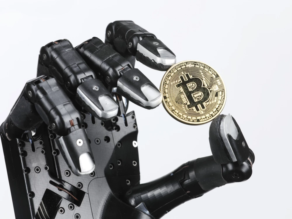 A robotic hand holding a gold bitcoin coin.
